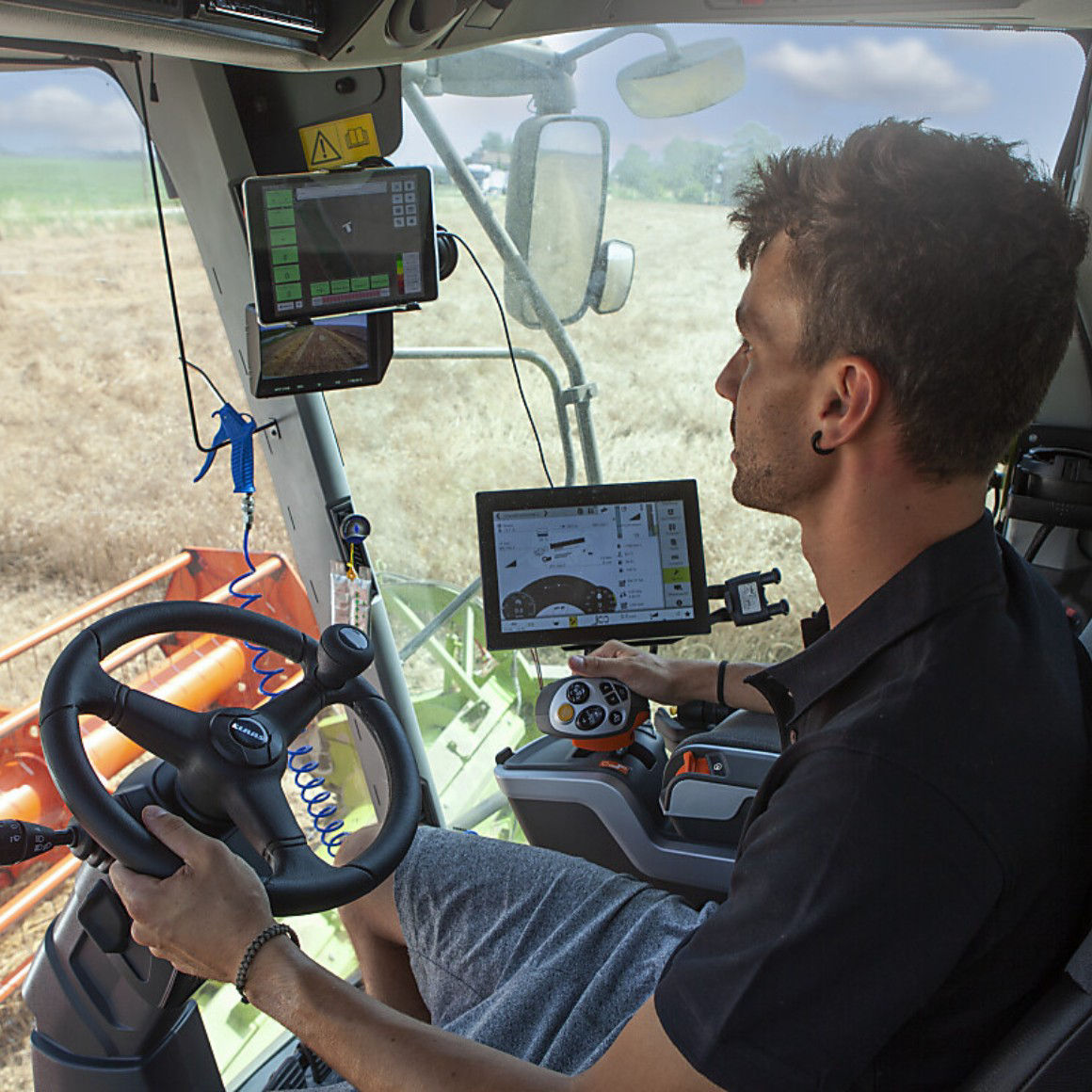 farmer in a tractor driving with monitors around him