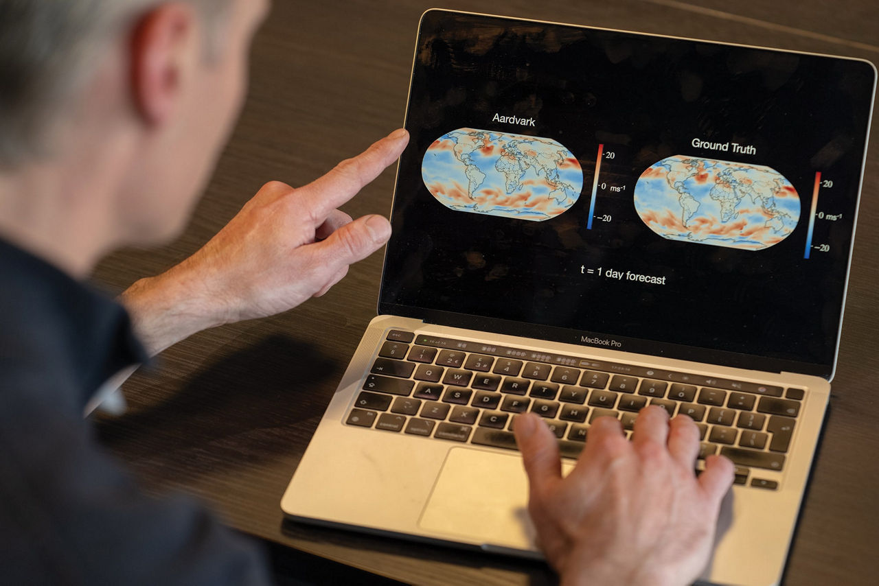 Person pointing at laptop showing Aardvark and Ground Truth weather forecast maps. 