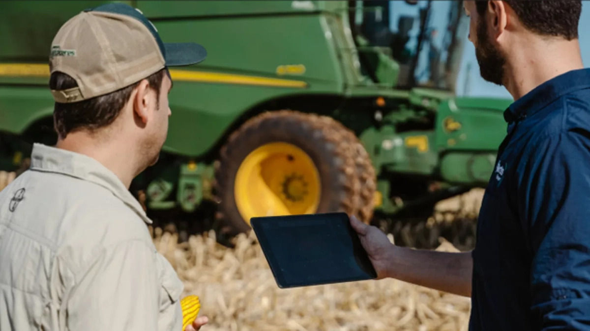 Homens mexendo no tablet no meio da plantação