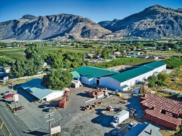 Birds eye view showing Gurpreet’s packing plant next to his acres of apple trees, and mountains in the background 