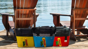 DEKALB branded cooler bags on a lakefront dock in front of Muskoka chairs.  