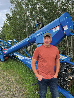 Colin Huseby standing in front of a blue grain auger on his farm