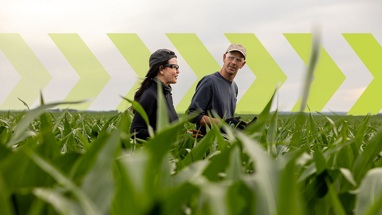 Male and female farmers walking through fields with green arrow pointing east