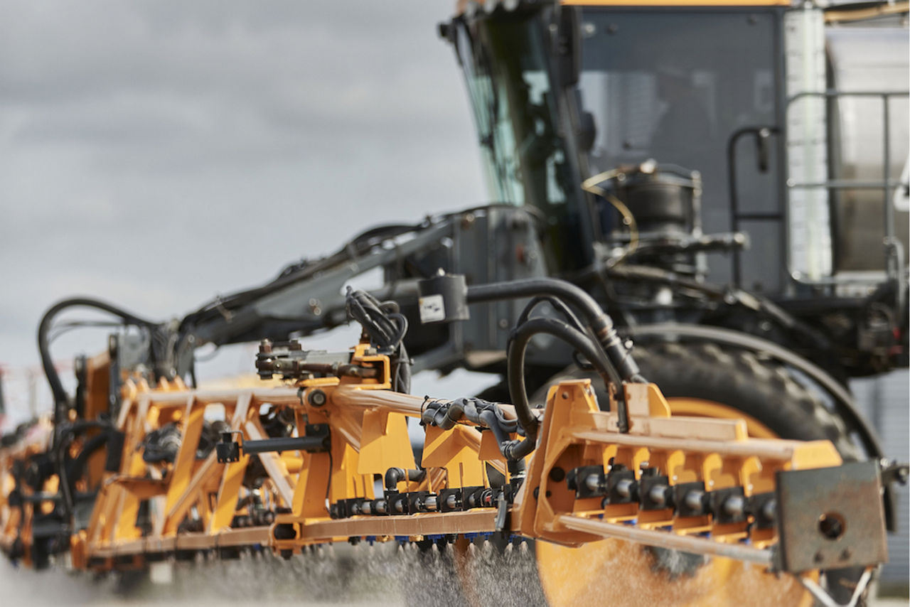 Close up image of a tractor working in a field to spray delaro complete and protect crops to increase yield