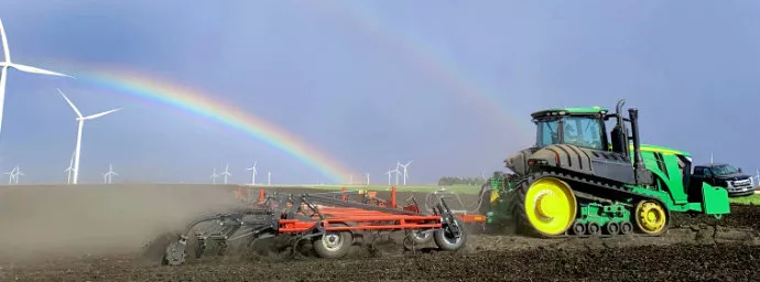 Tractor Tilling Field with Rainbows in the Backgroun