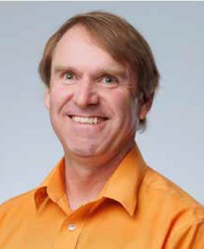 A headshot of Wayne Thompson, Executive Director of Western Grain Research Foundations. They are smiling and wearing an orange button up shirt.