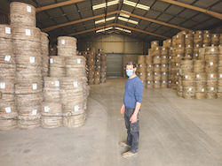 Martin Gosse De Gorre standing next to bales of flax fibre in a warehouse