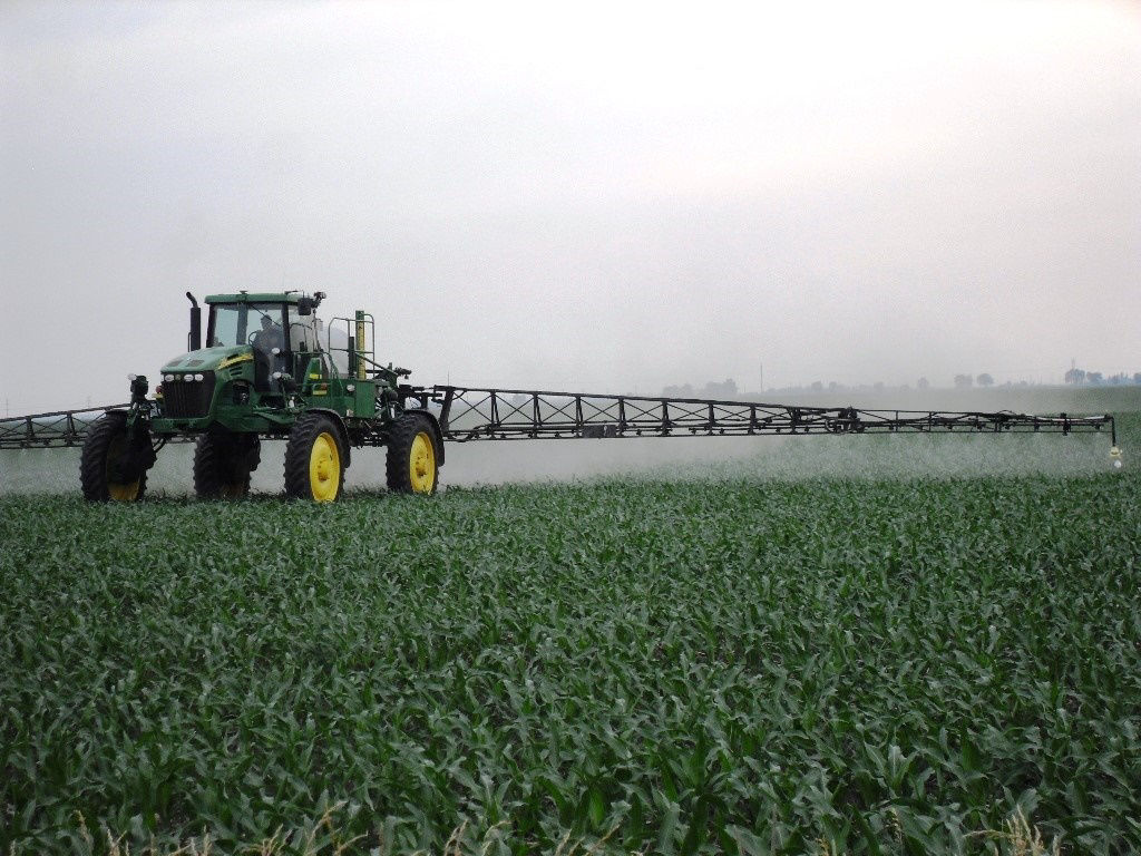 Grower in a tractor applying glyphosate herbicide early in the spring to a corn field.