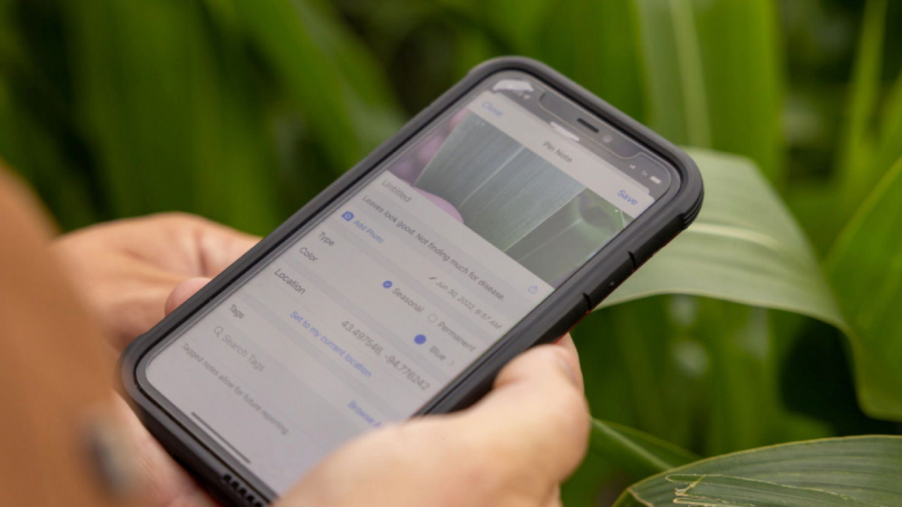A closeup view of hands holding a tablet on a field