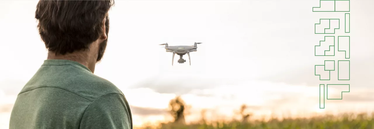 Man near a corn field flying a drone