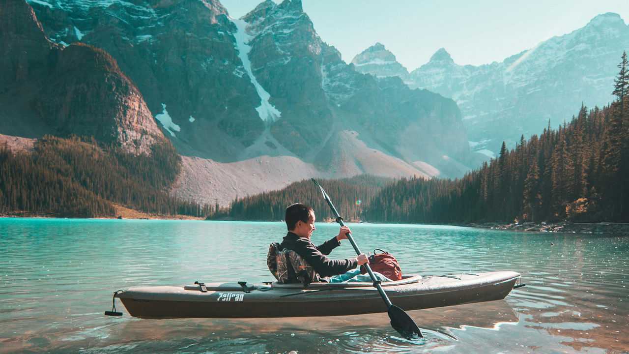 A person on a kayak with mountains in the background