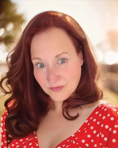 Selfie style image of Lisa Bishop-Spencer, the background features blurred greenery and sunlight. 
