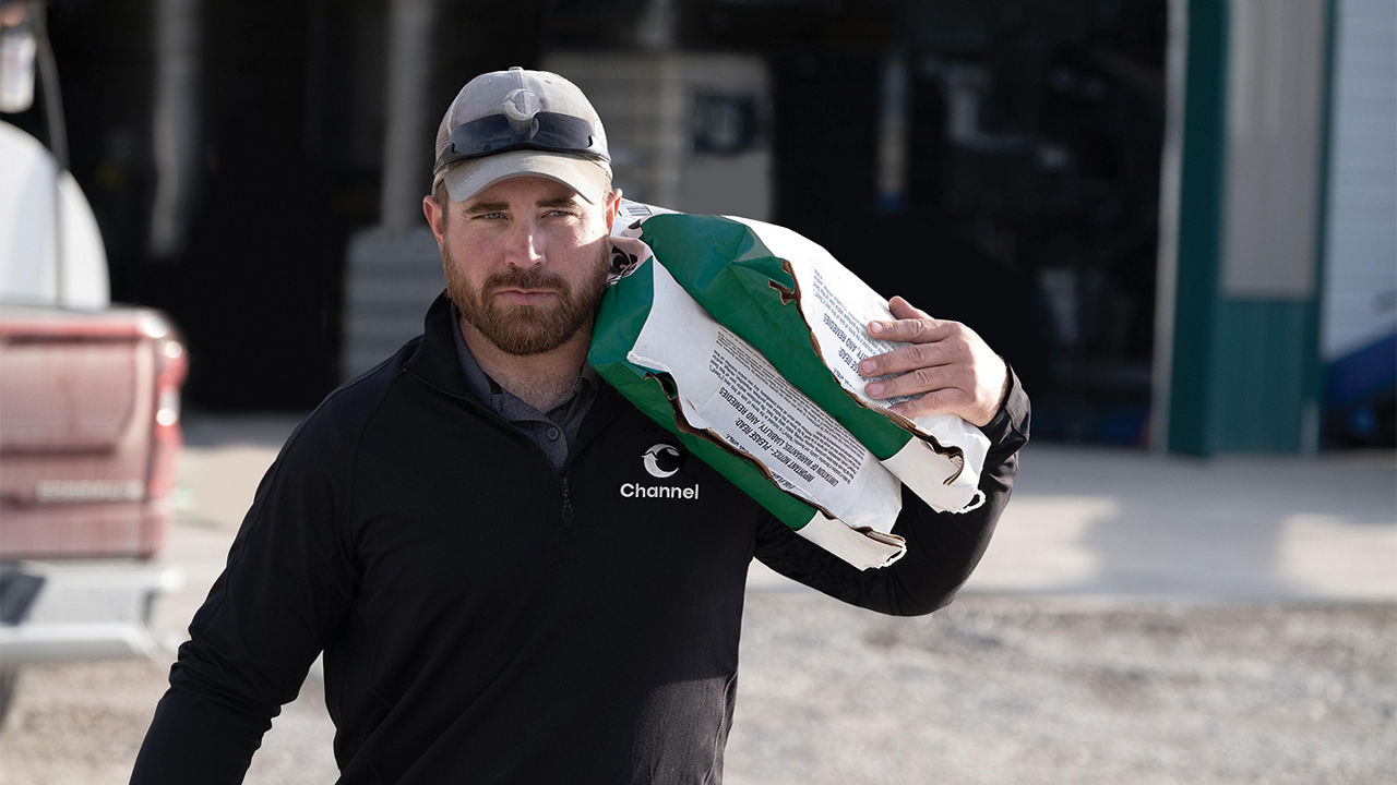 Channel Seedsman carrying two bags of seeds on their shoulder