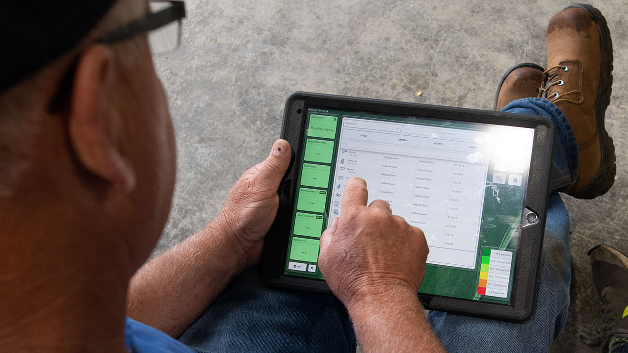 Farmer wearing brown shoes, looking at the Field View app on a tablet