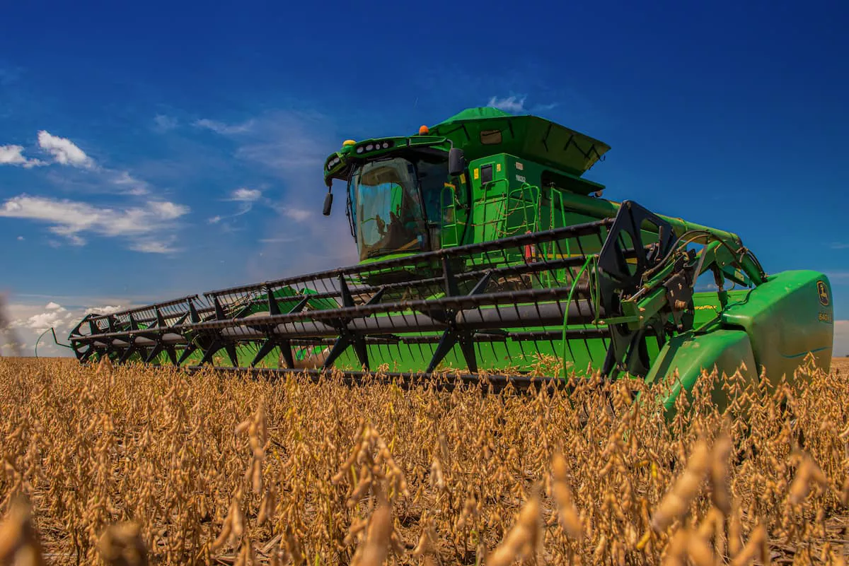 Imagem mostra uma colheitadeira verde em um campo agrícola 
