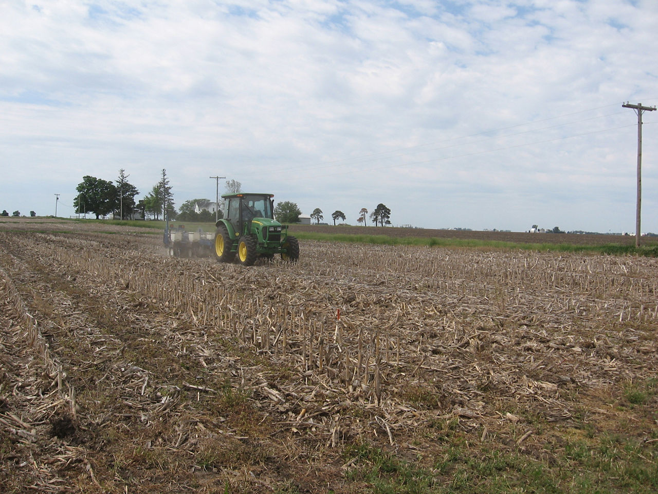 A farmer is planting seed in field with a no-till planter