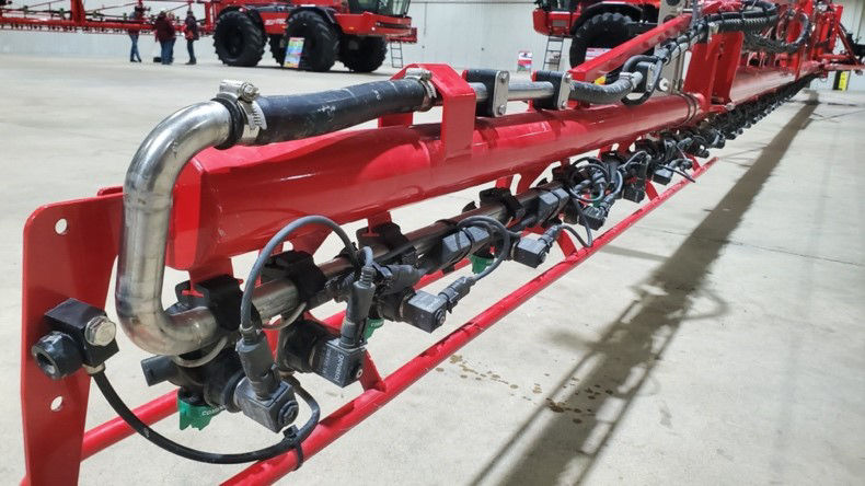 A recirculating boom with a prominent sweep visible on the end of a long red sprayer’s arm. 