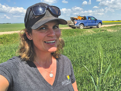 Wendy McDonald, senior agronomist with 360 Ag Consulting, taking a selfie in the field with a blue pickup truck in the background