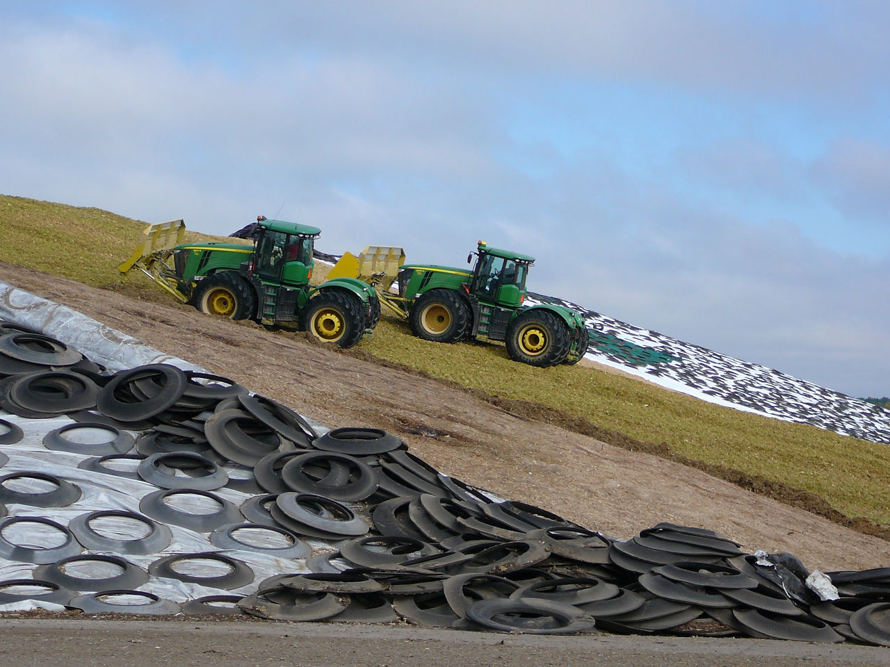 Two tractors dumping silage on a drive over pile