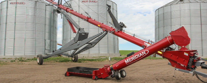 Grain auger with silos in the background 