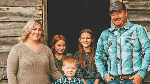 A Canadian farmer family standing by a barn