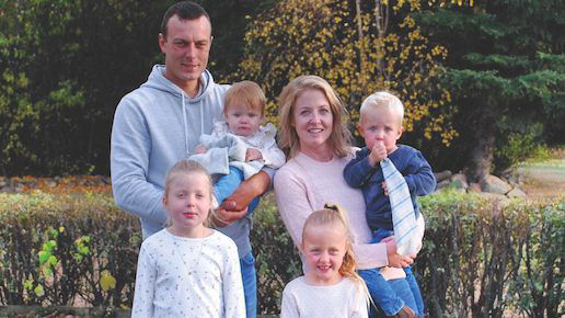 Parents posing for an outdoor family group photo with their four young children 