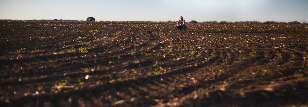 Farmer Crouched in Field Soil