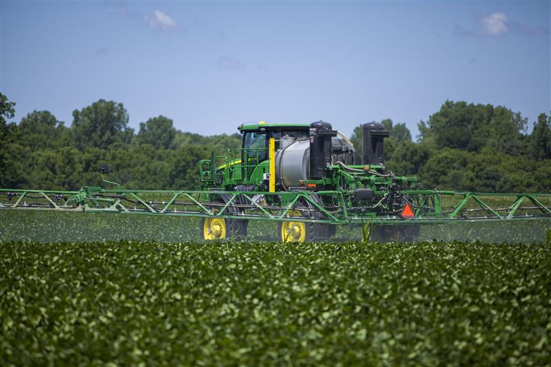 Sprayer operating in a green field under a blue sky.