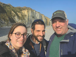 a group photo of Ken Coles, Martin Gosse De Gorre and his wife Helene standing next to a cliff on the beach